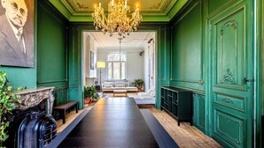 Et værelse med et langt, mørkt træbord, grønne vægge, en lysekrone og en pejs.