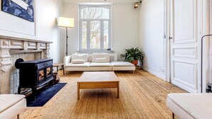 En stue med pejs, sofa og stort vindue.