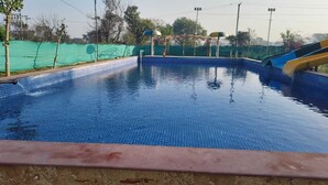 A swimming pool with clear blue water, a diving board, and a slide. - AN PERFECT STAYS IN THE LAP OF ARAVALI HILLS (Gurugram)