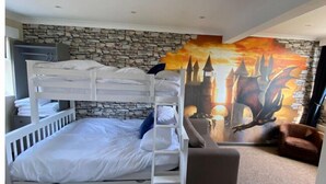 Ein Schlafraum mit Etagenbetten, einer Steinwand und einem Wandgemälde eines Schlosses.