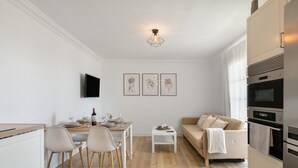 Eine moderne Küche mit Essbereich, einer Couch und einem an der Wand befestigten Flachbildfernseher.