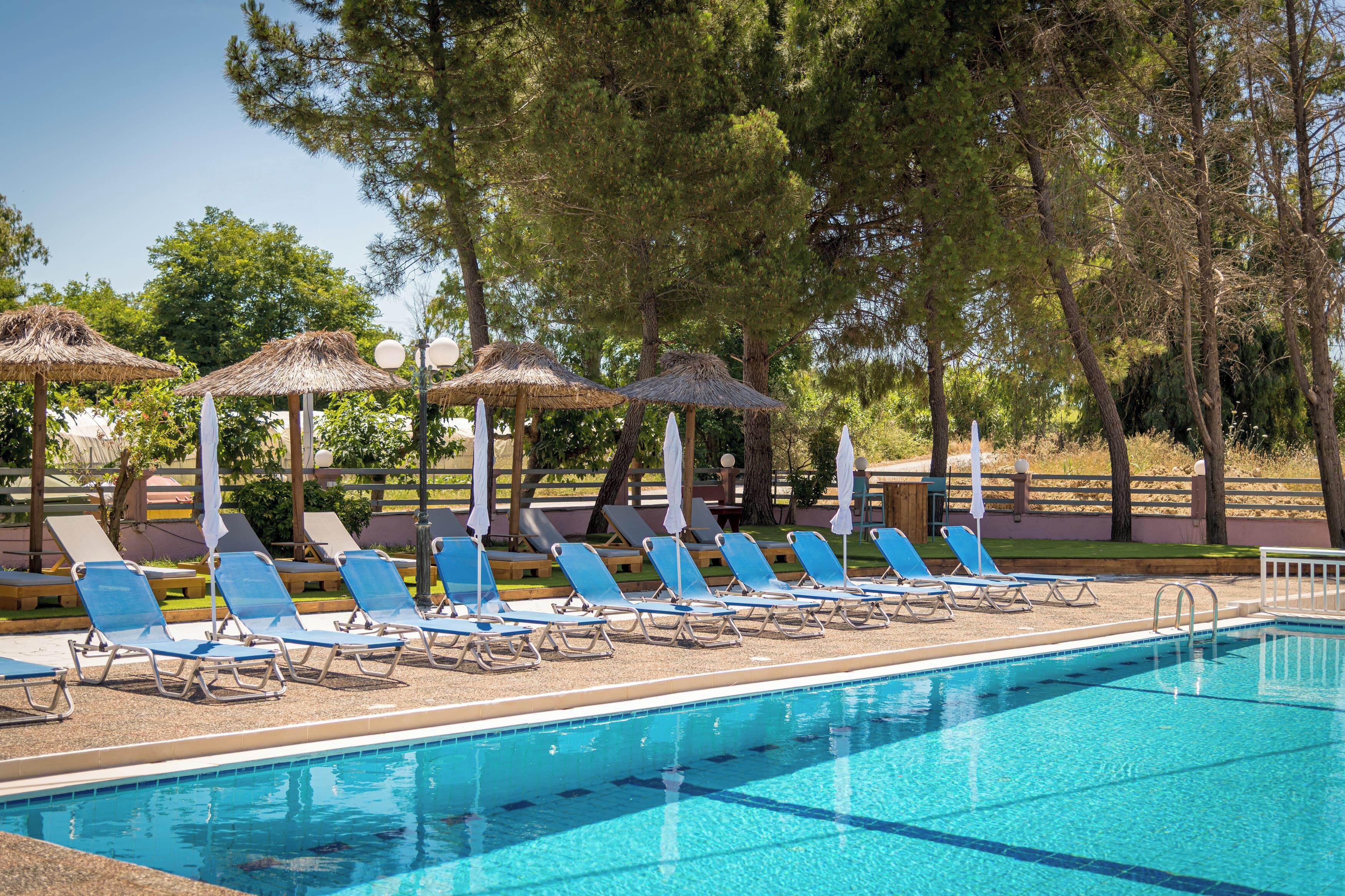 A swimming pool with lounge chairs and thatched umbrellas.