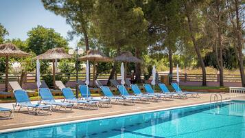 A swimming pool with lounge chairs and thatched umbrellas.