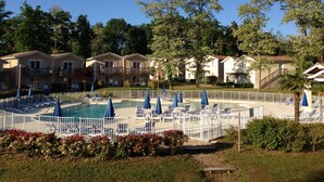 A pool area with lounge chairs and umbrellas, surrounded by a white fence. - Apt 5/6 pers.in the countryside, swimming pool, golf, horse riding (Barbaste)