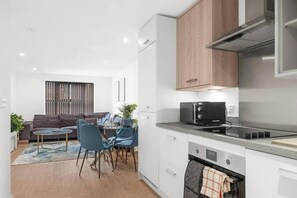 A modern kitchen with white cabinets, a microwave, and a stainless steel range hood. - Superb 1-bedroom apartment in cool Birmingham city center digbeth (Birmingham)