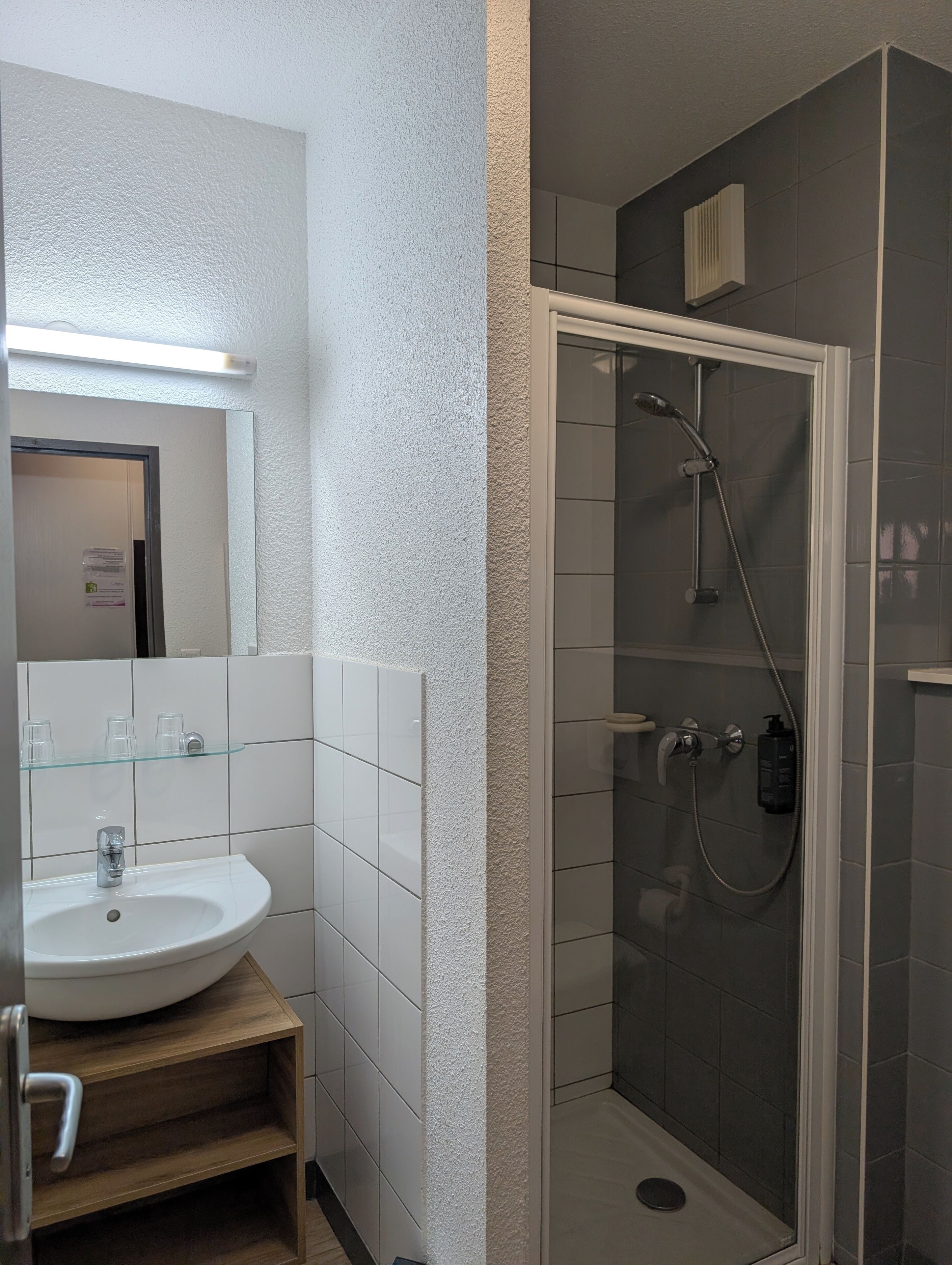 Ein Badezimmer mit Waschbecken, Spiegel und Duschkabine aus Glas.