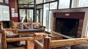 A cozy interior with wooden furniture, a fireplace, and large windows. - Villages vacances Cévéo de Bois d'Amont (Bois-d'Amont)