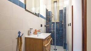 Ein Badezimmer mit Waschbecken, Holzschrank und Duschkabine aus Glas.