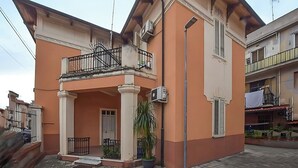 Ein zweistöckiges Gebäude mit einem Balkon, einer Tür und einem Blumentopf.