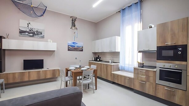 Eine moderne Küche mit Holzschränken, einem Einbauofen und einem Essbereich mit Tisch und Stühlen.