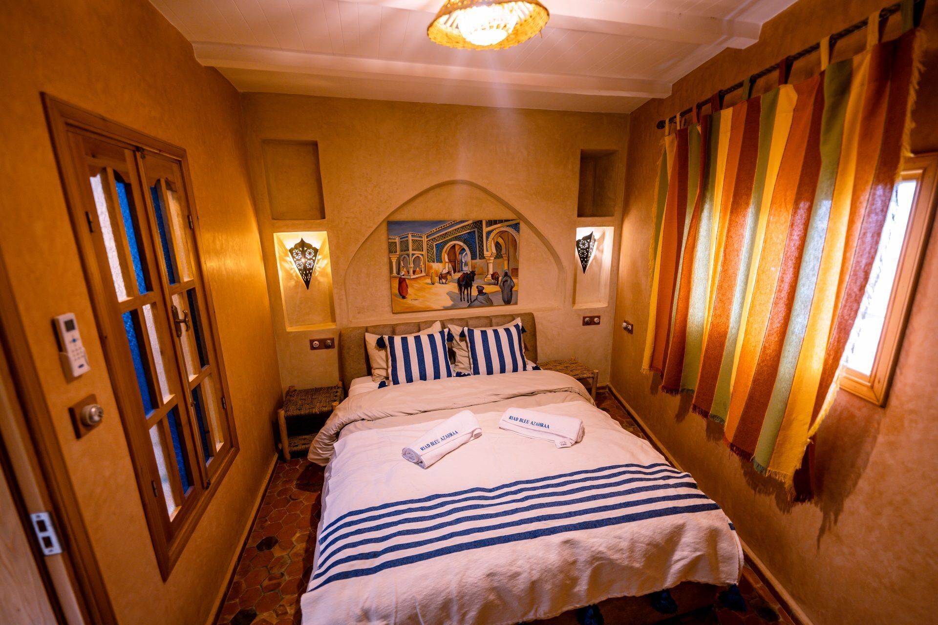 A hotel room with a bed, a nightstand, a wall-mounted artwork, and a door with a keypad lock.