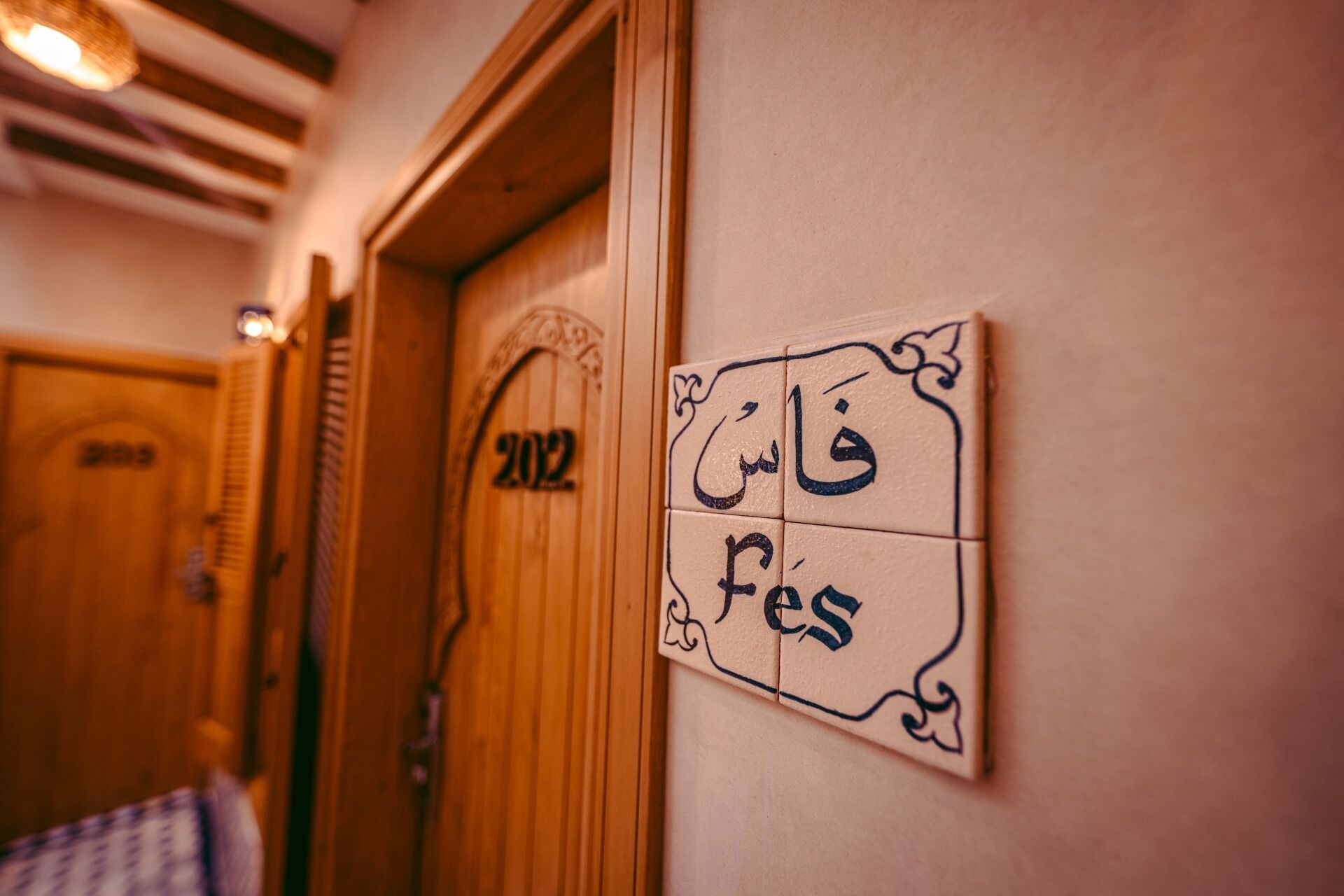 A hallway with a wooden door labeled '202' and a wall-mounted sign with Arabic text.