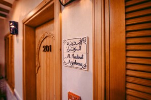 A wooden door with the number '201' and a sign with Arabic text 'Al Madinat Az Zahrat' on the wall. - Riad Bleu Azahraa (Safi)