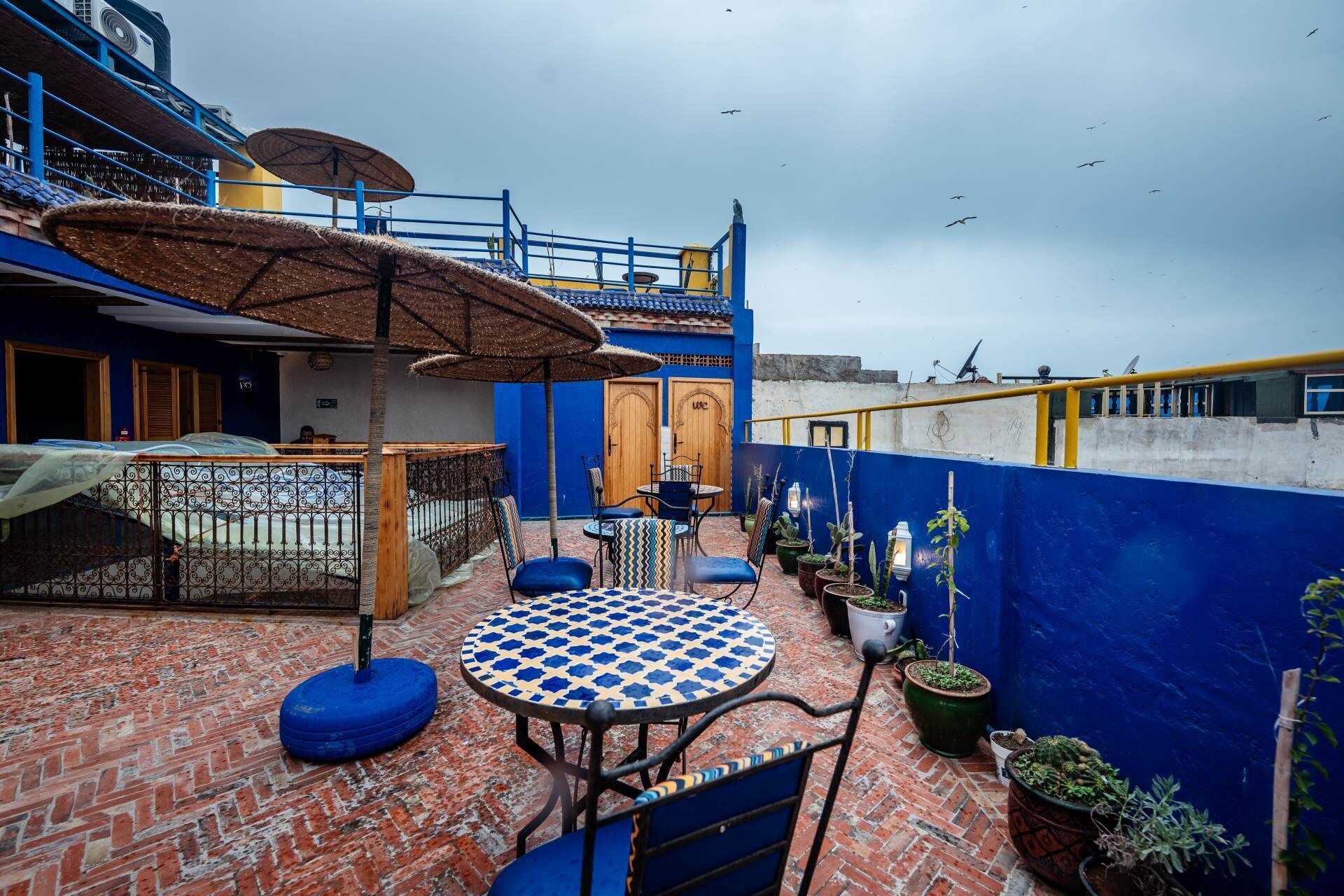 Une terrasse sur le toit, avec une table ronde, des chaises et des plantes en pot.