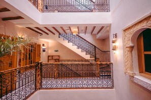 Un interior de varios niveles con una escalera, barandillas decorativas y un piso estampado.