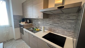 Eine moderne Küche mit eingebautem Ofen, einer Edelstahl-Spüle und einer Spritzschutzwand mit grauen Fliesen.