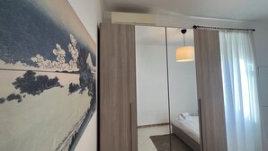Ein Hotelzimmer mit Bett, einem großen Spiegel, einem Gemälde an der Wand und einem Fenster mit Vorhängen.