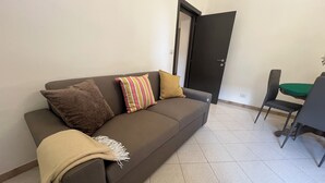 Ein Wohnzimmer mit einer Couch, einem Esstisch und Stühlen sowie einer Tür.