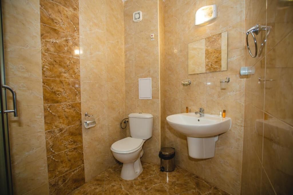 Casa de banho com sanita, lavatório e chuveiro.