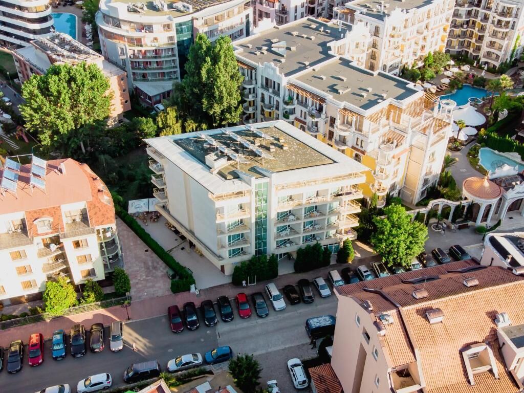 Un hotel de varios pisos con balcones, piscina y zona de estacionamiento.