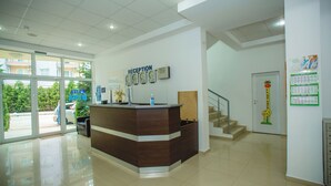 A reception desk with a sign, a staircase, and a calendar on the wall. - Deva Hotel - All Inclusive (Sunny Beach)