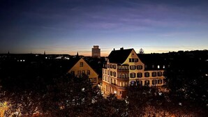 Een groot gebouw met meerdere verdiepingen en een opvallende toren, omringd door bomen en andere gebouwen.