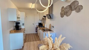 Een moderne keuken met witte kasten, een houten aanrechtblad en een hanglamp.