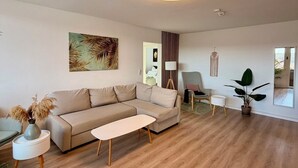 Een moderne woonkamer met een bank, salontafel en een groot raam.