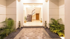 A hotel lobby with a checkered floor, a staircase, and potted plants. - ELIVAAS Mandovar Mountain Valley Retreat (Udaipur)