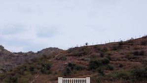A two-story building with a central archway, balconies, and a view of a hilly landscape. - ELIVAAS Mandovar Mountain Valley Retreat (Udaipur)