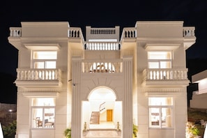 Un edificio imponente con un arco central, varios balcones y una escalera que conduce a un nivel superior.