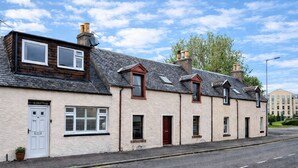 Une rangée de maisons traditionnelles à un seul étage, chacune dotée d’une porte bien visible portant l’inscription « IL SANTO », et une route dégagée devant.