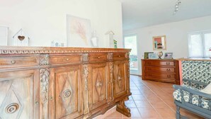 Una habitación amplia con un aparador de madera, un sofá estampado y un cómoda con cajones.