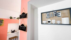 Una habitación con una pared rosa, una pared blanca con el letrero 'CAFE' y dos pizarras con la inscripción 'CAMERA-ROOM'.