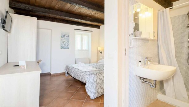 Une chambre à coucher comprenant un lit, une table de chevet, une fenêtre et une salle de bain avec un lavabo et une douche.