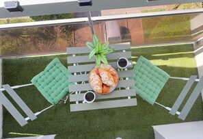A rooftop terrace with a table set for two, surrounded by green cushioned seating. - Pearly EuroPoint (Saint-Louis)
