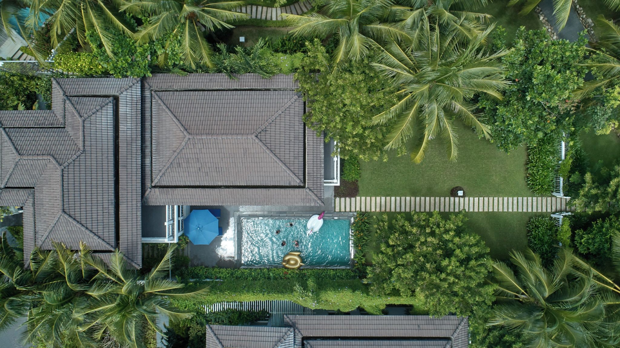 A resort with multiple buildings, a swimming pool, and lush tropical vegetation.