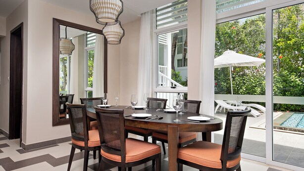 A dining area with a large table, chairs, and a view of a swimming pool. - Villa Premier Village Da Nang Abogo (Da Nang)