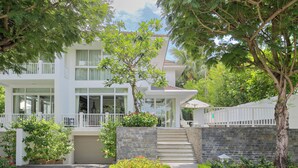 A two-story building with a white exterior, a balcony, and a stone wall. - Villa Premier Village Da Nang Abogo (Da Nang)