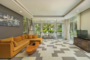 A modern living room with a sectional sofa, a coffee table, and a television. - Koaniva Villa Premier Village Da Nang (Da Nang)