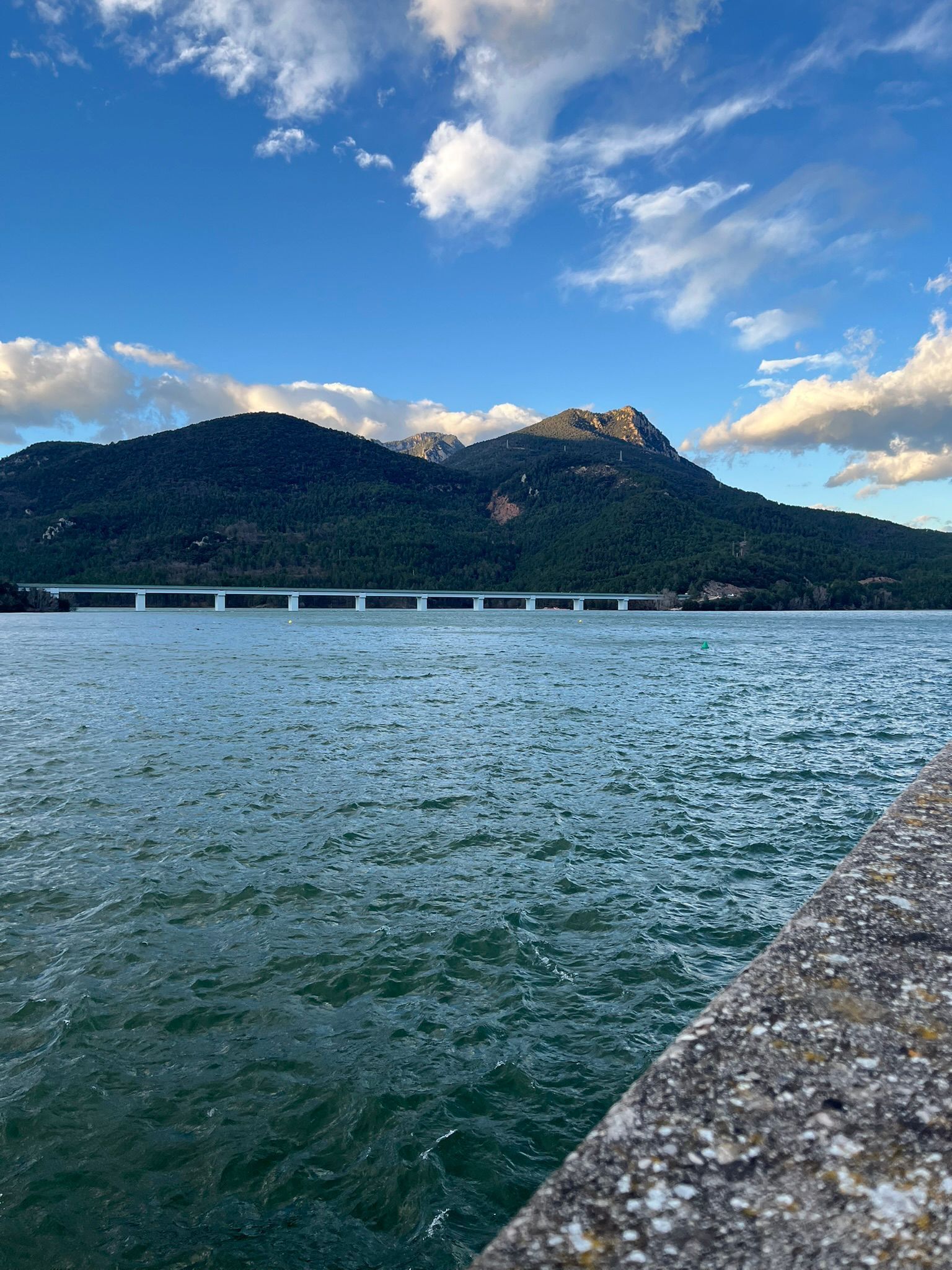 A body of water with a bridge and a mountain in the background.