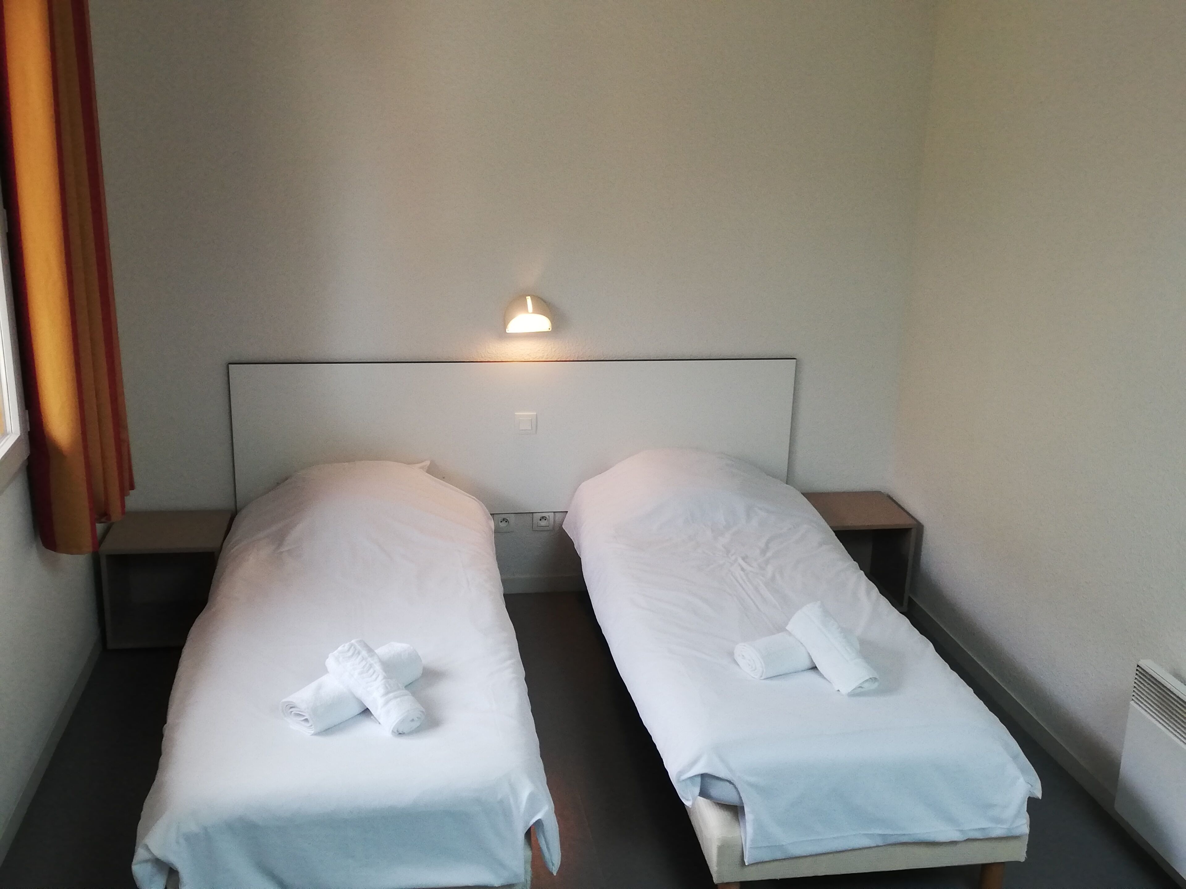 A twin room with two single beds, each with a pillow and a rolled towel.