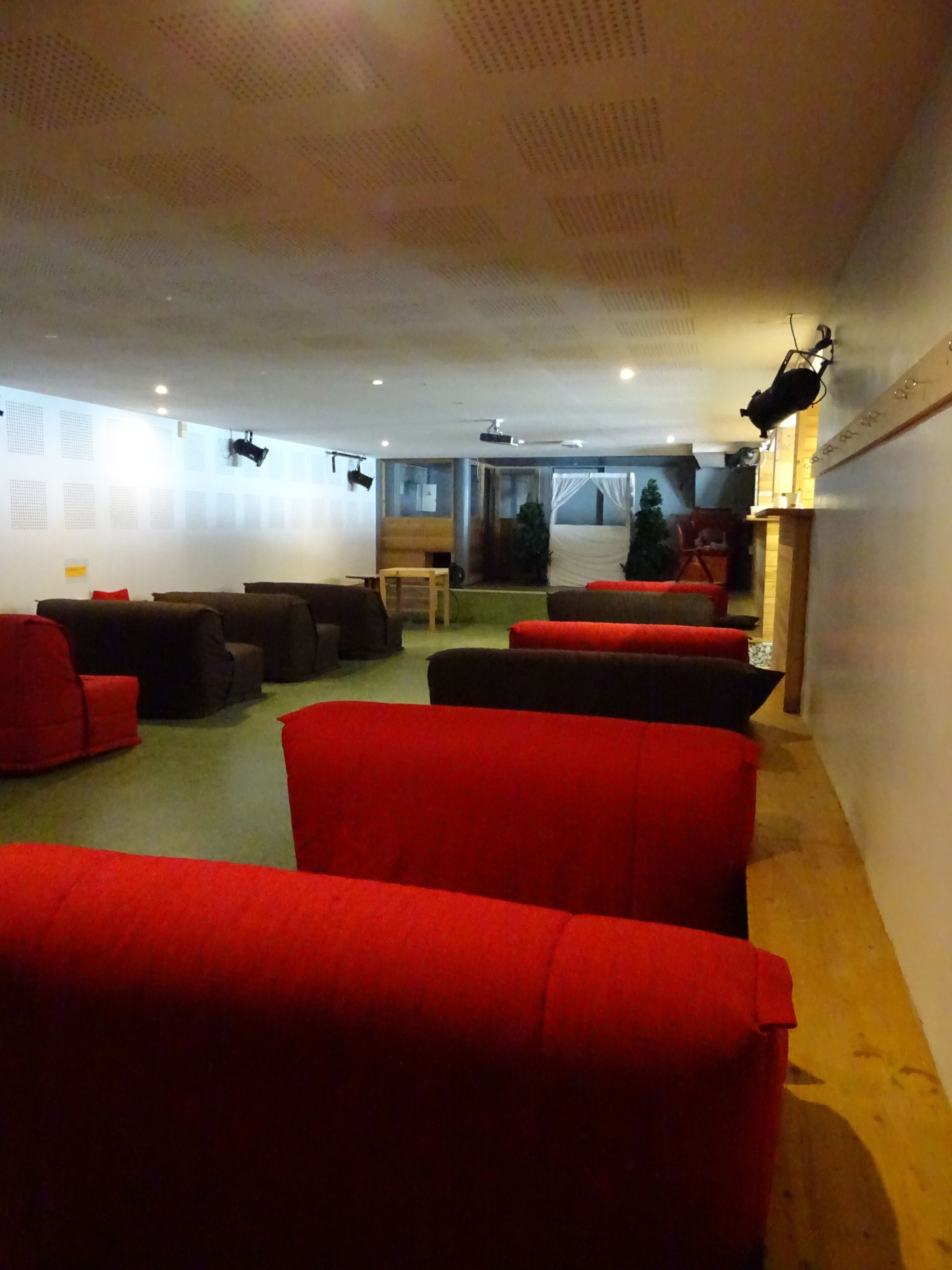 A room with multiple red sofas, a wooden chair, and a small table.