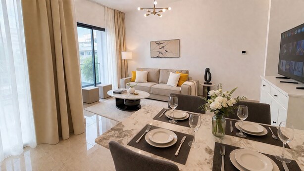 A modern living room with a sofa, a dining table set for two, and a television. - Oni Residence Apartment (Limassol)