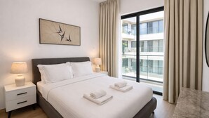 A modern hotel room with a large bed, two bedside lamps, a nightstand, a marble side table, and a large window with curtains. - Oni Residence Apartment (Limassol)