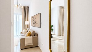 A modern living room with a sofa, a painting, and a large mirror. - Oni Residence Apartment (Limassol)