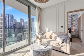 Ein modernes Wohnzimmer mit einer Couch, einem runden Couchtisch und Blick auf eine Stadtlandschaft durch große Fenster.