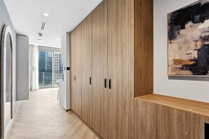 Ein Flur mit Holzboden, einem großen Schrank mit mehreren Türen und einem modernen, abstrakten Gemälde an der Wand.