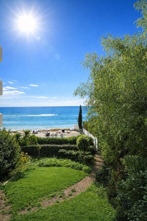 A coastal view with a clear sky, a grassy area, and a seating arrangement facing the sea. - Gulf Beach Apartment (Limassol)