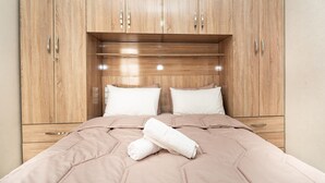 Ein Schlafzimmer mit einem Holfischschrank, einem Bett mit einer beigefarbenen Bettdecke und zwei Kissen.